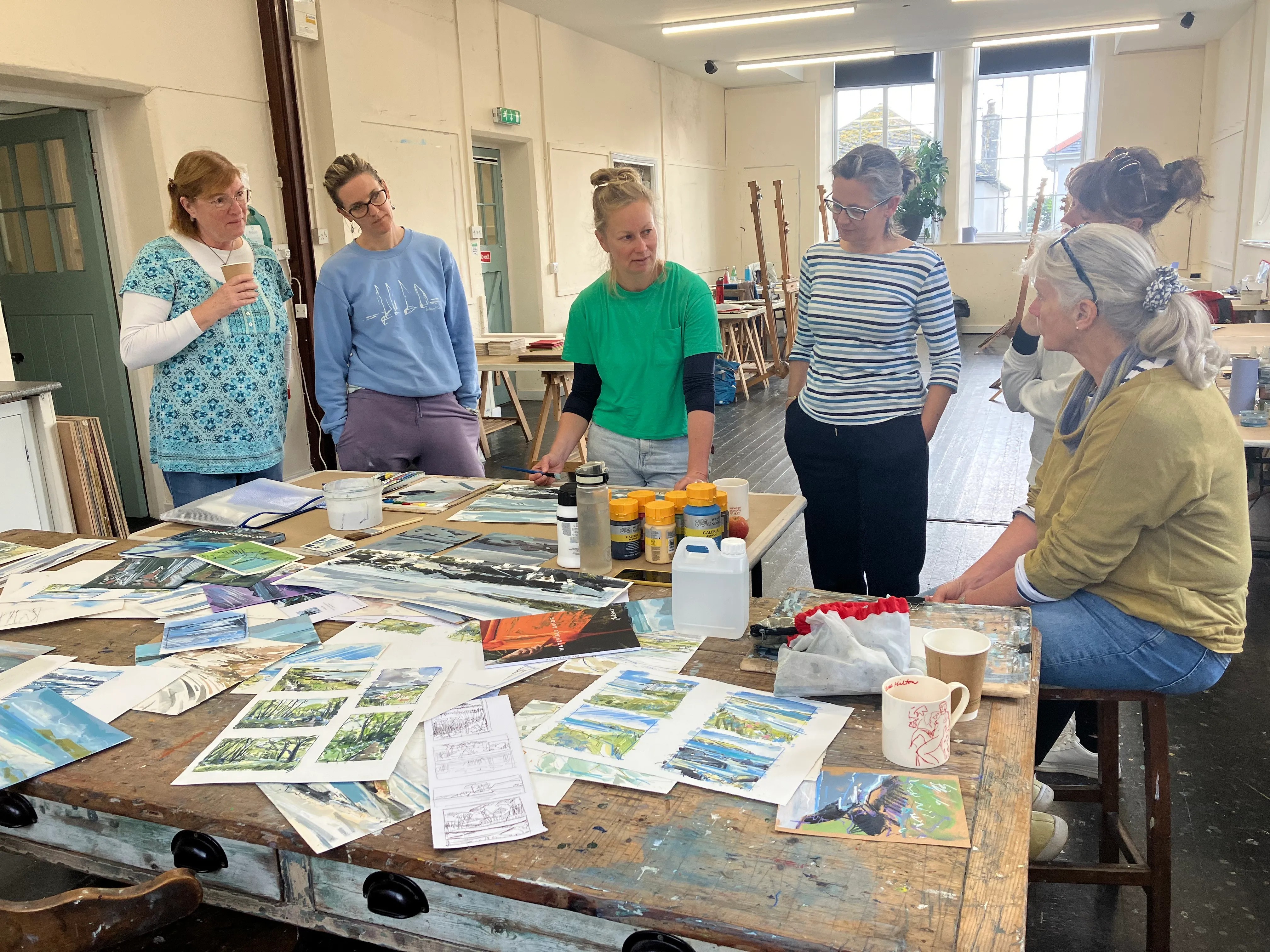 A group of artists surrounding a table covered in artworks